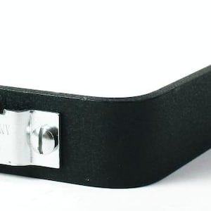 Puede incluir: Soporte metálico negro con una curva en ángulo recto. Una placa de metal plateado está sujeta con tornillos, con el texto "MADE IN GERMANY BY Rollei". El soporte tiene varios agujeros.