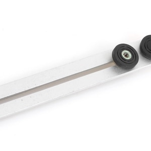 May include: A silver metal ruler with two black knobs on the end. The ruler has a groove running down the centre.