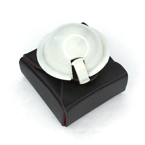 May include: A white plastic dome shaped flash diffuser for photography, in a black leather case with red stitching.