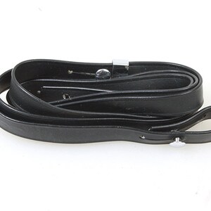 May include: A black leather camera strap with a silver metal buckle.