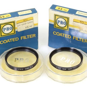 Könnte beinhalten: Zwei 55 mm Objektivfilter in ihrer Originalverpackung. Die Filter sind mit "PRO Coated Filter" beschriftet und befinden sich in durchsichtigen Plastikbehältern. Ein Filter ist mit "C.S." und der andere mit "Diff." beschriftet.