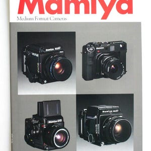 May include: A Mamiya Medium Format Cameras brochure featuring the bold red text Mamiya at the top. The cover displays four black medium format cameras, specifically the Mamiya RZ67 Pro II, a Mamiya model, the Mamiya 645, and the Mamiya RB67.