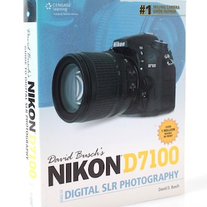 May include: A softcover instructional book titled David Busch's Nikon D7100 Guide to Digital SLR Photography. The white cover features a black Nikon D7100 camera with a lens, blue graphic accents, and text indicating over 1 million books in print.
