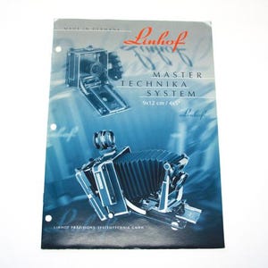 Puede incluir: Un folleto en blanco y negro para la cámara Linhof Master Technika System. El folleto presenta una foto de la cámara y el texto "Linhof Master Technika System 9x12 cm / 4x5"