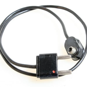 May include: A black electrical cord with two black connectors on each end. One connector has a red dot and two metal prongs. The other connector has a single round metal prong.