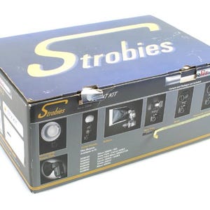 Könnte beinhalten: Dunkelblaue rechteckige Box für ein Strobies-Licht-Kit. Der Schriftzug "Strobies" ist in Gold gehalten. Die Box zeigt Bilder der Komponenten des Kits und Produktinformationen.