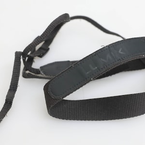 May include: Black camera strap with the word "LMK" printed on it.