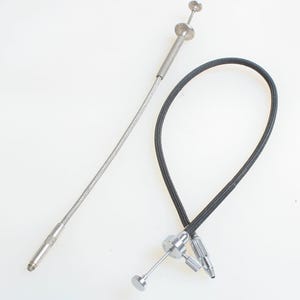 May include: Two camera accessories: a silver metal cable release with a flexible, braided cable and a silver metal remote shutter release. The cable release has a textured grip and a button on the end. The remote shutter release has a button and a threaded end.