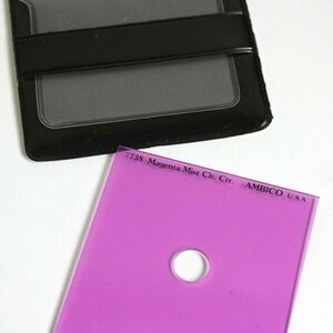 May include: A black case with a clear window and a magenta filter. The filter has a circular hole and text that reads "7738 Magenta Mist Clr. Ctr. AMBICO USA."