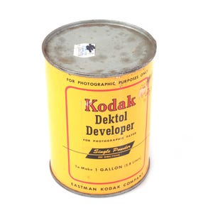 Könnte beinhalten: Eine gelbe Vintage-Dose mit Kodak Dektol Entwickler. Die Dose hat einen roten Rand mit dem Text "Kodak Dektol Developer" und "For Photographic Paper". Sie ist für 3,8 Liter ausgelegt.