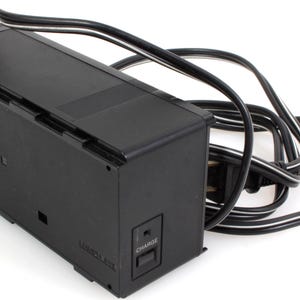 May include: Black rectangular battery charger with a black and white power cable. The charger has a "CHARGE" button and the text "LONDON AIRE" is visible. Designed for electronic devices.