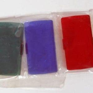 Puede incluir: Un conjunto de cinco filtros rectangulares de plástico en una funda de plástico transparente. Los filtros están dispuestos en fila y presentan colores distintos: un filtro texturizado transparente, verde oscuro, morado, rojo brillante y amarillo.