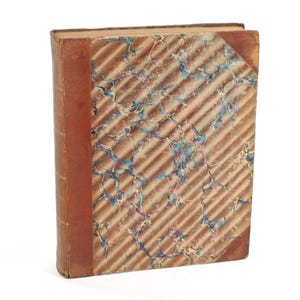 May include: A vintage book with a brown leather cover and a marbled paper design in shades of blue, red, and yellow.