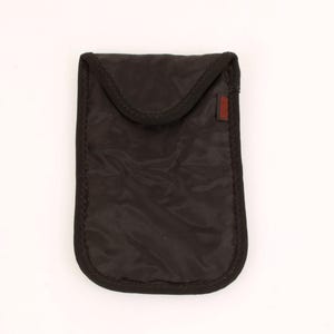 May include: A black, rectangular pouch with a rounded bottom and a flap closure. The pouch is made of a smooth, possibly nylon, material with a stitched black border. A small, rectangular brown tag is on the right side.