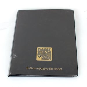 Può includere: Lega per negativi 6x6 cm nera con logo dorato "Dark Room 2001".