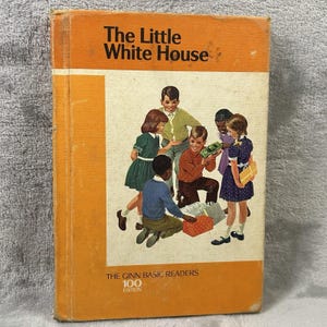 May include: Vintage children's book titled "The Little White House" with an orange cover. The cover illustration depicts a group of children gathered around gifts. The book is part of "The Ginn Basic Readers 100 Edition."