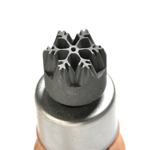 May include: A close-up of a black metal snowflake-shaped stamp. The stamp is mounted on a silver metal base.