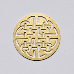 May include: A gold-colored metal pendant with a Celtic knot design. The knot is intricate and detailed, and the pendant is circular in shape.