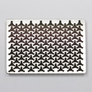 May include: A silver metal plate with a repeating pattern of black triangles. The triangles are arranged in a staggered pattern, creating a geometric design.