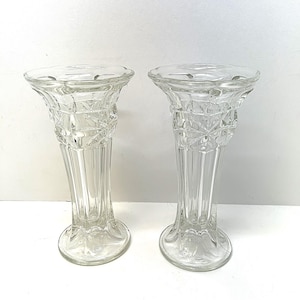 Könnte beinhalten: Zwei klare Glasvasen mit geschliffenem Glasdesign. Die Vasen haben eine breite Öffnung und einen schmalen Boden.