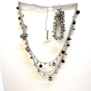 Peut inclure: Un collier multi-rangs en argent avec des perles rayées noir et blanc et des perles noires. Le collier est superposé et possède une chaîne délicate. Le collier est accompagné d'un bracelet en argent avec des perles noires. L'étiquette indique "Haskell".