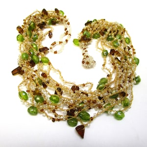 Peut inclure: Collier multi-rangs avec des perles vertes et brunes. Le collier est fait de petites perles et a un aspect crocheté.