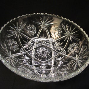 Könnte beinhalten: Eine klare Glasschüssel mit einem Sternmuster. Die Schüssel ist groß und hat einen gewellten Rand.