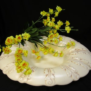 May include: A white ceramic bowl with a decorative, raised design. The bowl is filled with a bouquet of yellow flowers.