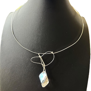 May include: A silver choker necklace with a clear crystal pendant. The pendant is faceted and has a light blue hue.