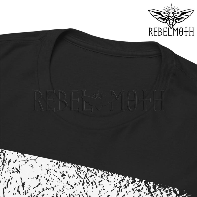 May include: A black t-shirt featuring a round neckline and the text REBEL MOTH embossed across the chest. A logo depicting a moth with a skull pattern is positioned in the upper right corner, and a white textured graphic pattern is at the bottom.