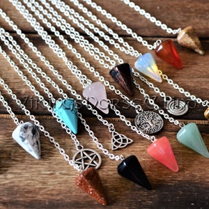 Könnte beinhalten: Eine Sammlung von Kristallpendeln mit silbernen Ketten. Die Pendel sind in verschiedenen Farben und Formen erhältlich, darunter Grün, Blau, Rosa und Braun. Einige haben Metallanhänger, wie ein Pentagramm, ein Lebensbaum und eine Spirale.