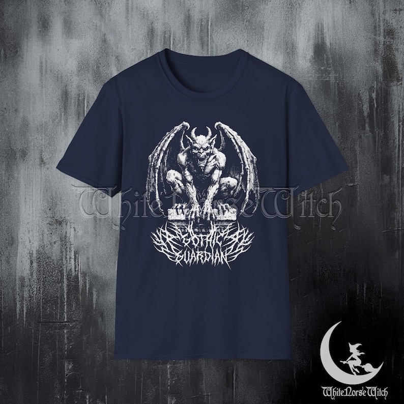 May include: Navy blue t-shirt featuring a white graphic of a gargoyle with spread wings, perched on a stone structure. Below the gargoyle is the text "DARK GOTHIC GUARDIAN" in a stylized font. The shirt has short sleeves.