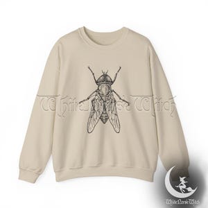 May include: A beige sweatshirt with a black and white illustration of a fly on the front.