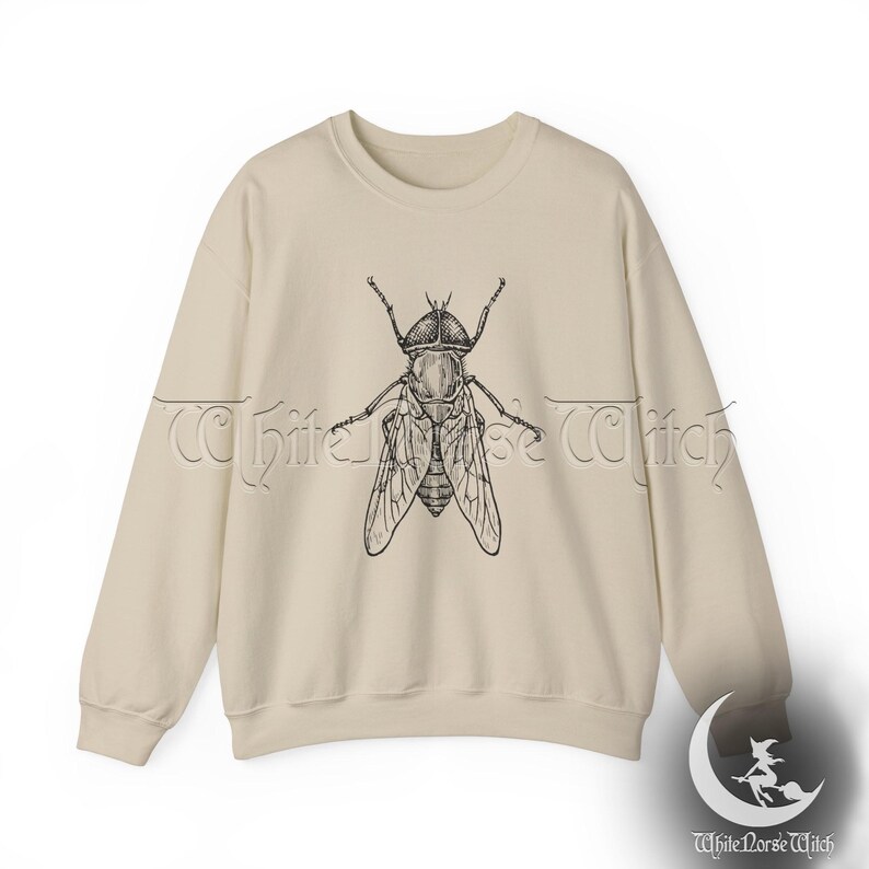 May include: A beige sweatshirt with a black and white illustration of a fly on the front.