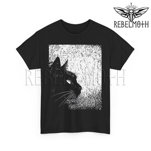 May include: A black short-sleeve t-shirt featuring a white graphic print of a cat in profile. The cat is positioned on the left side of a rectangular, textured white background. The text REBELMOTH is printed in black above the cat graphic.