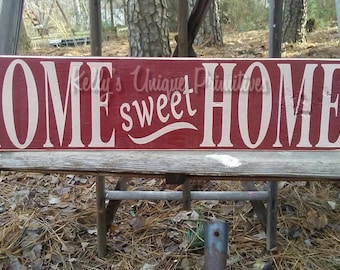 May include: A wooden sign with the words "Home sweet Home" painted in white on a red background.