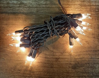 May include: A string of brown Christmas lights with clear bulbs. The lights are coiled up and ready to be hung.