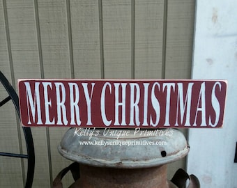 Puede incluir: Un letrero de madera rojo con letras blancas que dice "Feliz Navidad".