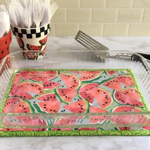 May include: A glass baking dish with a watermelon print hot pad underneath. The hot pad has a green border and a green swirl pattern.