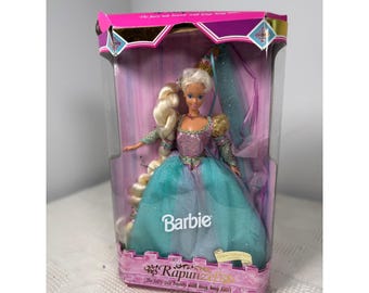 May include: A Barbie doll in a box, featuring long blonde hair, a purple and teal glittery gown, and a gold crown. The packaging displays the text Barbie and Rapunzel, with the subtitle The fairy tale beauty with long, long hair.