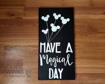 May include: Black canvas with white Mickey Mouse heads painted as balloons. The text "HAVE A MAGICAL DAY" is written in white paint.