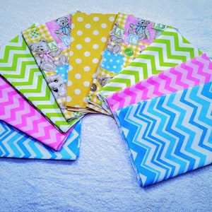 May include: A set of ten fabric squares featuring various patterns, including yellow polka dots, green and white chevron, pink and white chevron, blue and white chevron, and a patchwork design with teddy bears and letters.