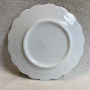 May include: White milk glass plate with a scalloped edge. The plate is plain and has no design.