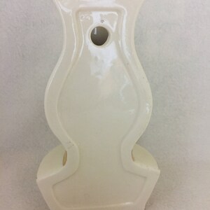 May include: White ceramic wall vase shaped like a lamp with a hole in the back for hanging.
