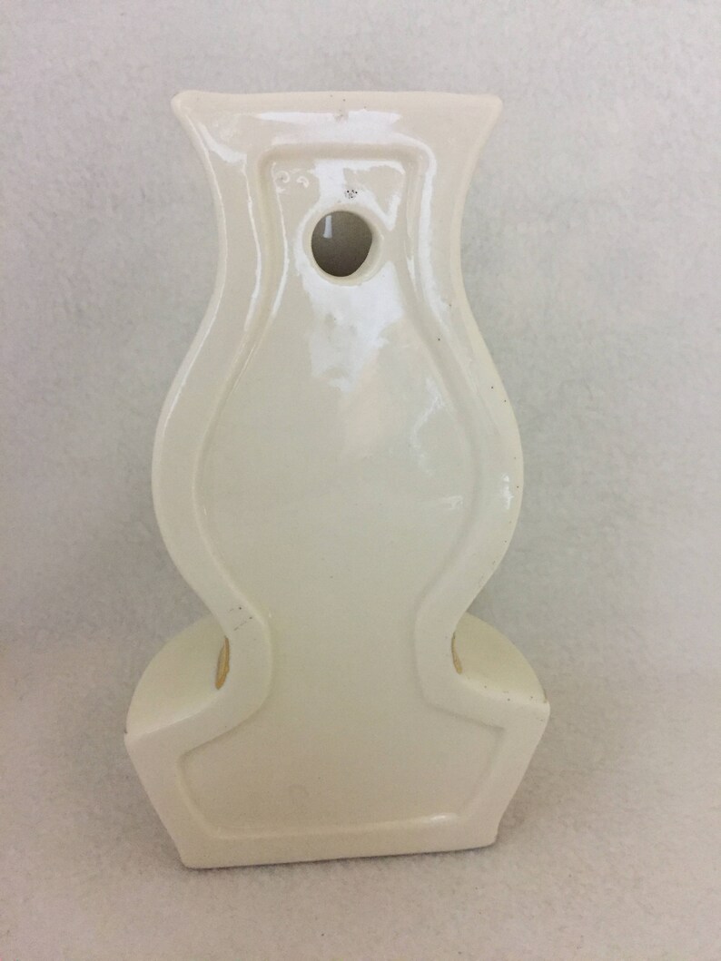 May include: White ceramic wall vase shaped like a lamp with a hole in the back for hanging.