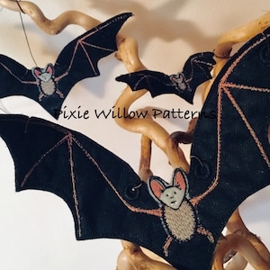 May include: Three black felt bats with embroidered faces hanging from a branch. The bats have pink noses and black eyes. The text "Pixie Willow Patterns" is visible in the image.
