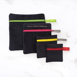 Può includere: Quattro pochette nere con cerniera e tiretti di diversi colori. Le pochette sono allineate dalla più grande alla più piccola. La pochette più grande ha un tiretto verde, la successiva ha un tiretto rosa, la successiva ha un tiretto giallo e la pochette più piccola ha un tiretto rosso. Le pochette sono etichettate "Pixie Willow Patterns".