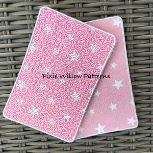 May include: Two pink fabric squares with white stitching. One square has a white star pattern, the other has a white squiggly line pattern. The text "Pixie Willow Patterns" is visible on the squiggly line square.