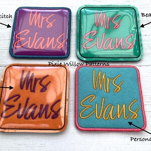 May include: Four square fabric patches with different colored backgrounds and stitching. The patches are personalized with the text "Mrs Evans" in different colors and fonts. The patches are for crafts and sewing projects.