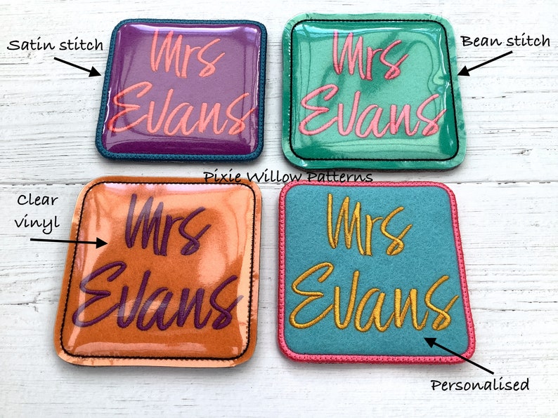 May include: Four square fabric patches with different colored backgrounds and stitching. The patches are personalized with the text "Mrs Evans" in different colors and fonts. The patches are for crafts and sewing projects.